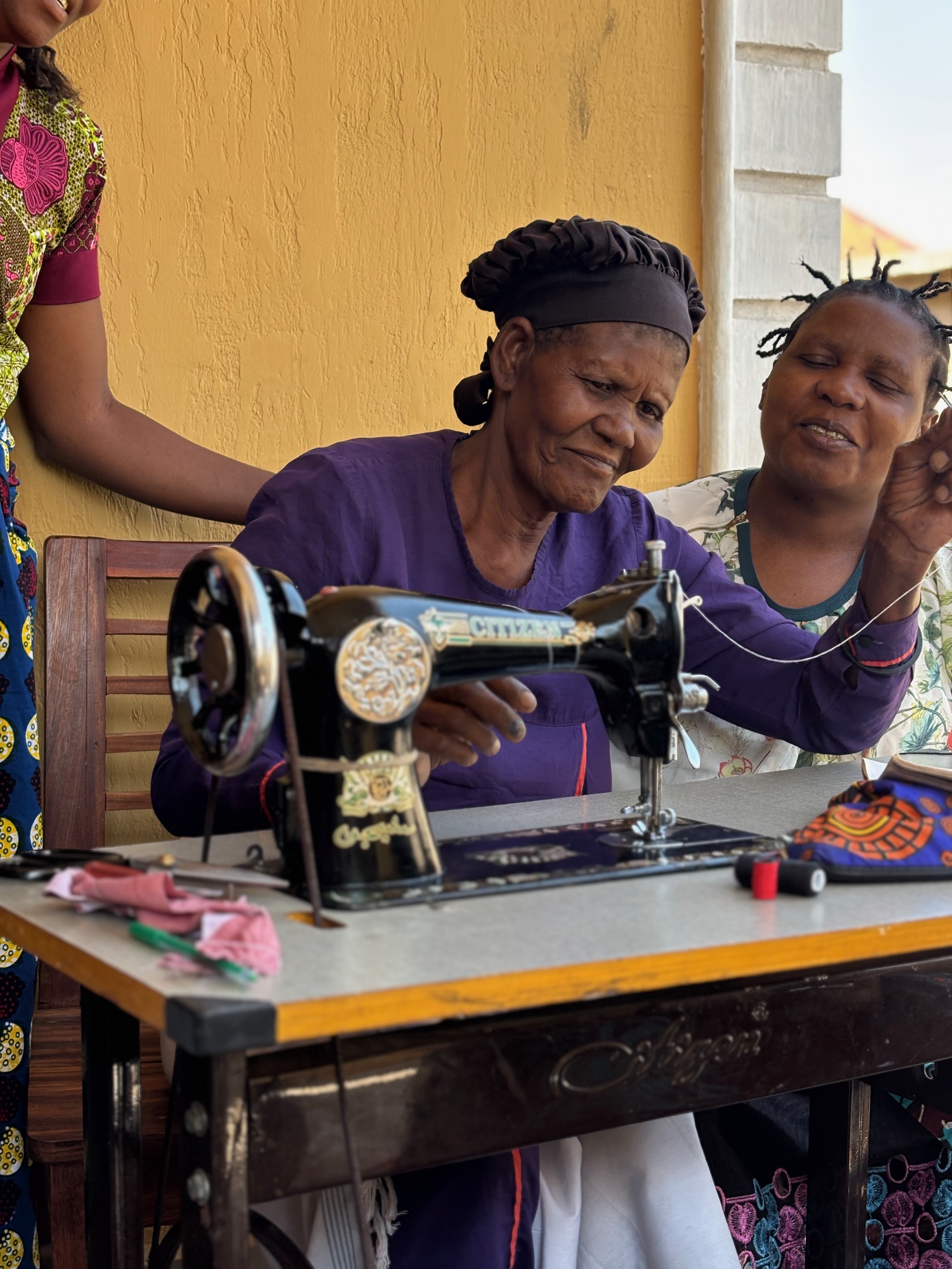 A woman working at a sewing machine with others beside her